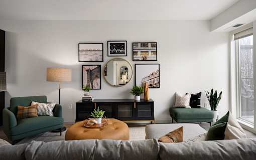 A living room with a grey sofa, a green chair, a wooden coffee table, and a mirror on the wall.