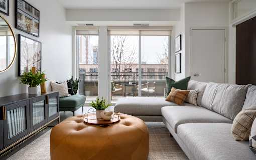 A living room with a grey couch, a brown ottoman, and a green chair.