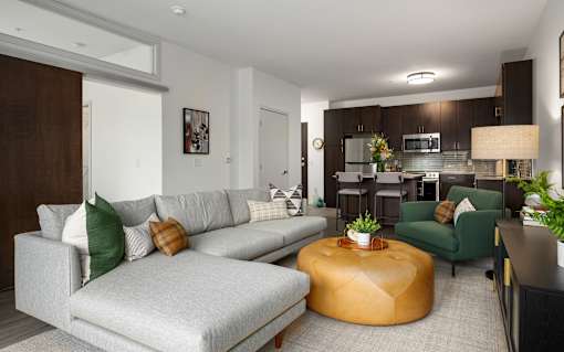 A modern living room with a grey sofa and a yellow ottoman.