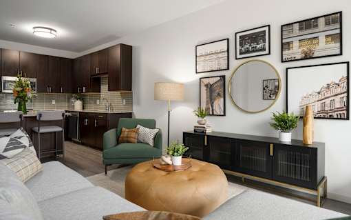 A living room with a grey sofa, a green armchair, a wooden coffee table, and a wall with framed pictures.