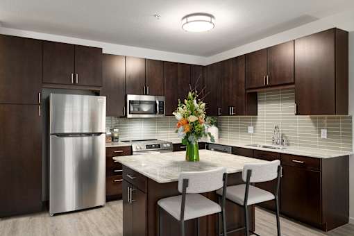 A modern kitchen with a stainless steel refrigerator, microwave, and white countertops.