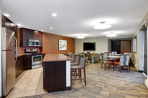 A kitchen with a refrigerator, microwave, oven, and a dining table with chairs.