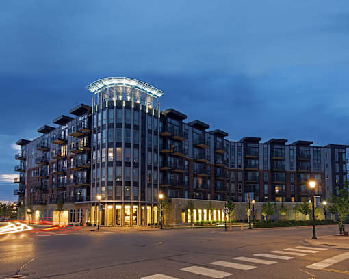 A modern building with a curved top is illuminated at night.