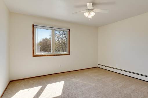 A room with a window and a ceiling fan.