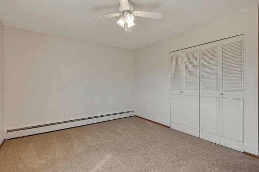 A room with a ceiling fan and white walls.