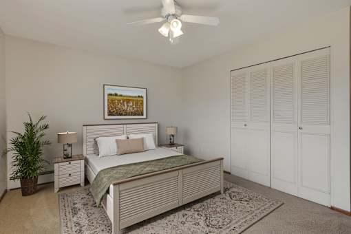 A bedroom with a bed, nightstands, and a ceiling fan.