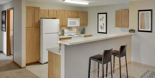 A kitchen with a white fridge, bar stools and a white counter.