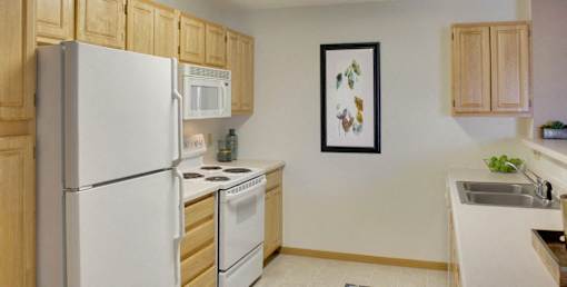 A kitchen with a white refrigerator, microwave, and oven.
