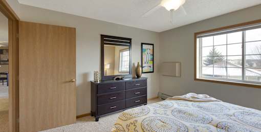 A bedroom with a bed, dresser, and mirror.