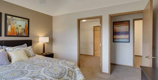 A bedroom with a patterned bedspread and a painting on the wall.