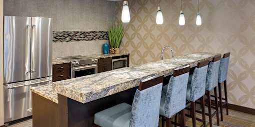 A kitchen with a marble countertop and bar stools.