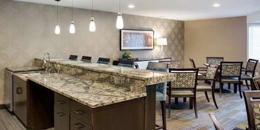A kitchen with a marble countertop and a dining table with chairs.