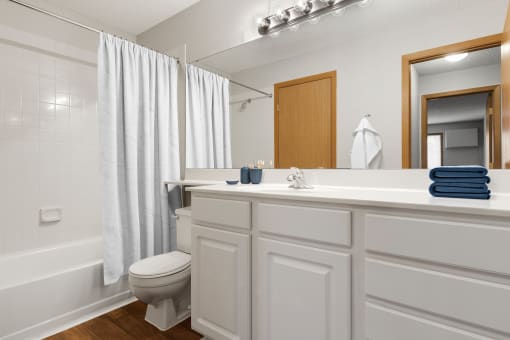 a bathroom with a white shower curtain and a white toilet next to a white bathtub  at Park Pointe, St. Louis Park, MN, 55426