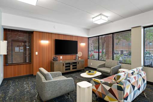 A modern living room with a grey sofa, a grey armchair, a wooden cabinet, a TV, and a coffee table.