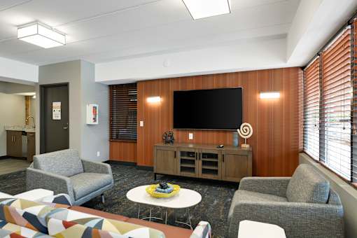 A modern lounge area with a television, chairs, and a coffee table.