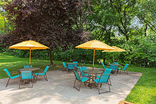 A patio with blue chairs and yellow umbrellas.