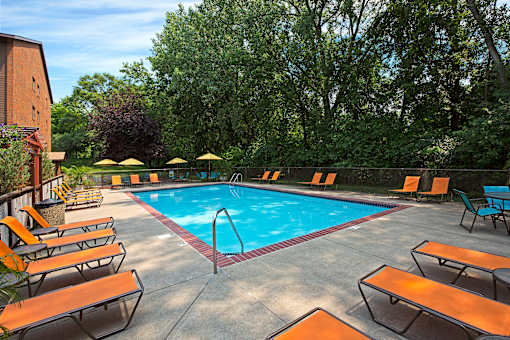 A pool surrounded by orange lounge chairs and umbrellas.