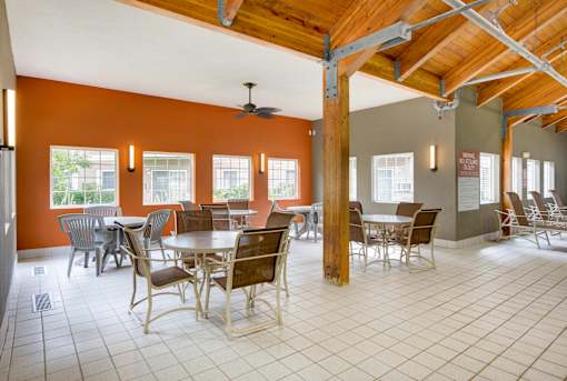 A large room with tables and chairs and a ceiling fan.