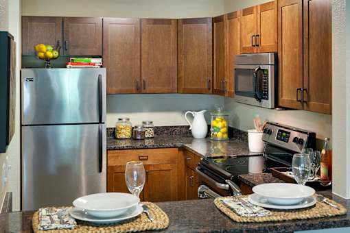 A kitchen with a refrigerator, microwave, and oven.