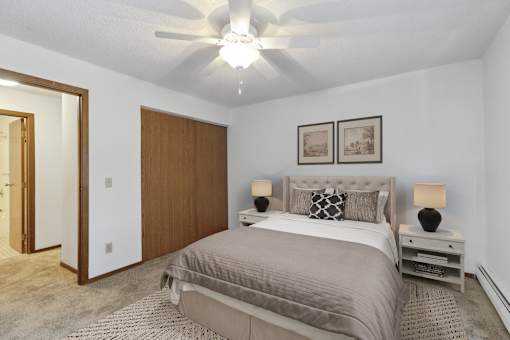 A bedroom with a bed, nightstand, and two pictures on the wall.