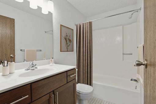 A bathroom with a white sink and brown wood cabinets.