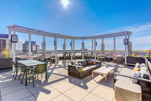 A sunny day on a rooftop patio with tables and chairs.
