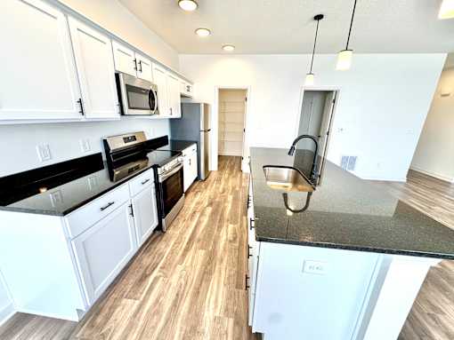 A kitchen with white cabinets and black countertops.at Concord Crossing, Lafayette, IN  