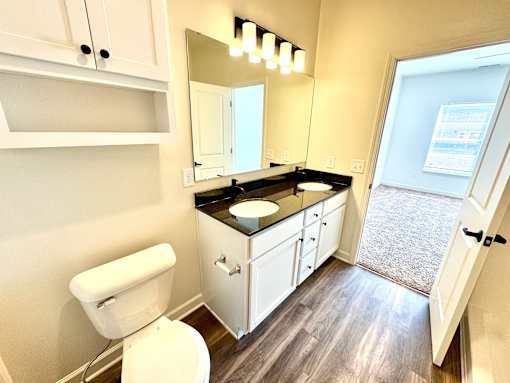 A bathroom with a toilet, sink, and mirror.at Concord Crossing, Lafayette  