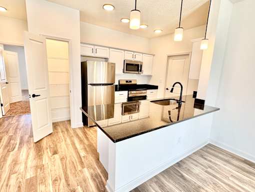 A kitchen with a stainless steel refrigerator and a black countertop.at Concord Crossing, Indiana  