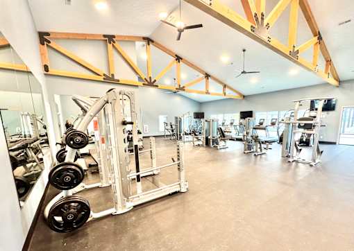 A gym with a variety of equipment including a weight rack and a squat rack.at Concord Crossing, Lafayette Indiana  