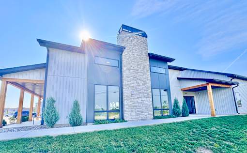 A modern house with a stone chimney and a large glass window.