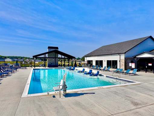 A large outdoor swimming pool with lounge chairs and a building in the background.