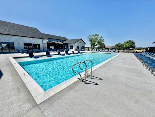 A large outdoor swimming pool with a diving board and lounge chairs.