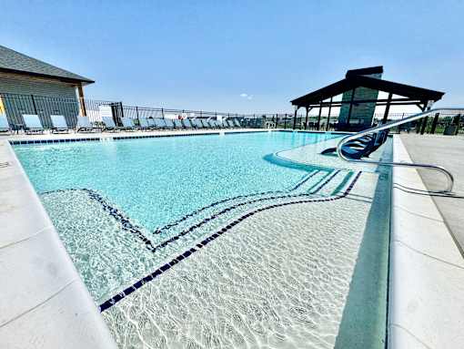A large swimming pool with a diving board and lounge chairs.