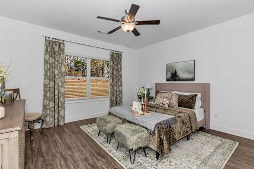 A bedroom with a bed, a bench, and a ceiling fan.