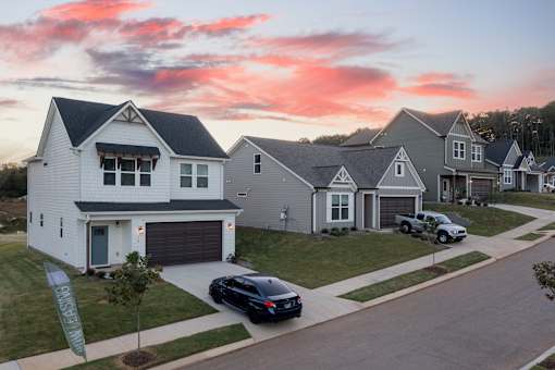 A row of houses with cars parked in front.
