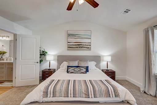 A bedroom with a large bed and a ceiling fan.