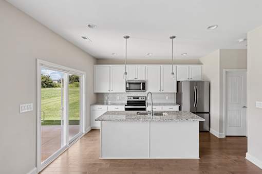 A kitchen with white cabinets and a marble countertop.