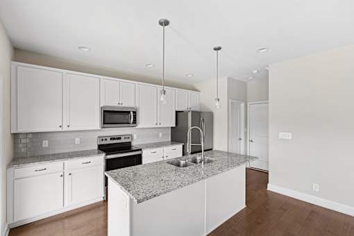 A kitchen with white cabinets and a granite countertop.