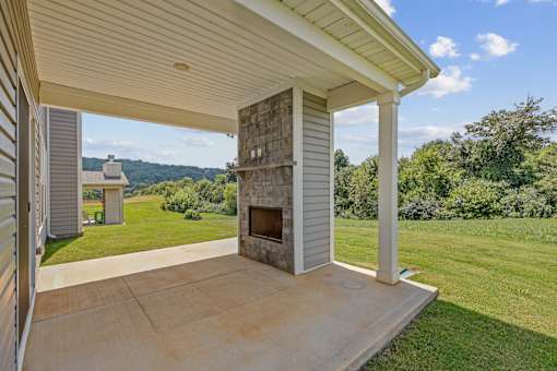 A covered patio with a fireplace and a view of the backyard.