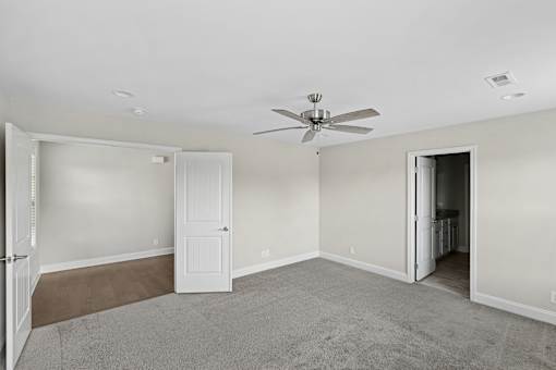 A room with a ceiling fan and carpeted floor.