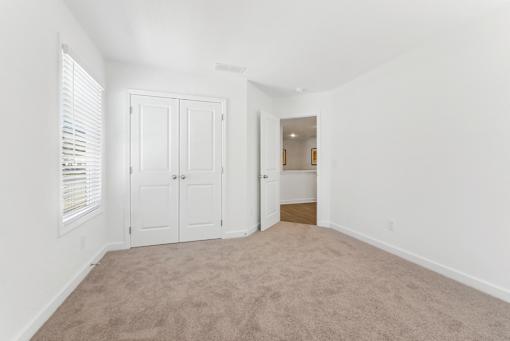Bright bedroom with plush carpet and ample closet space