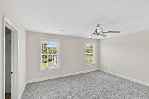 A room with a ceiling fan and two windows.