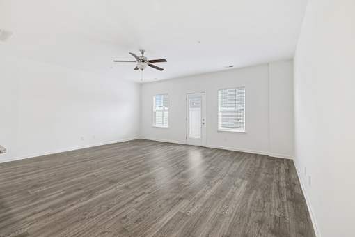 A room with a ceiling fan and wood flooring.