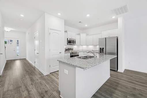 A modern kitchen with a granite countertop and stainless steel appliances.