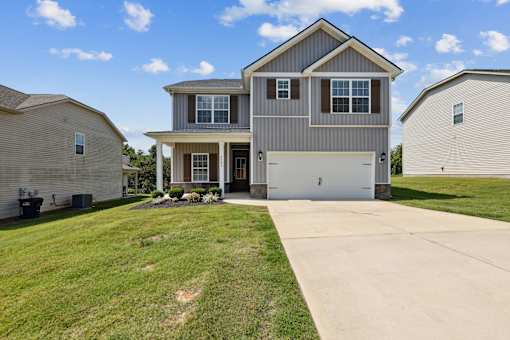 A large house with a garage is surrounded by a well-kept lawn.