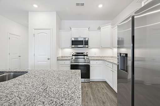 A kitchen with white cabinets and a patterned floor mat.