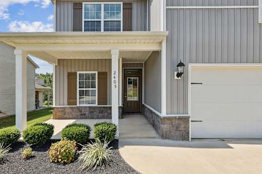 A house with a grey siding and a white garage door.