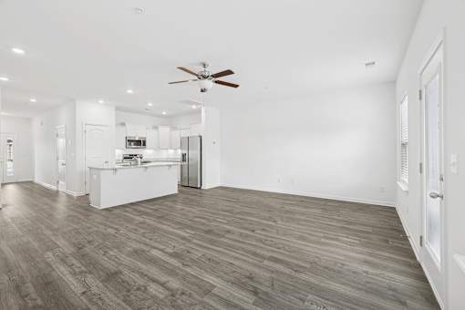 A spacious room with a ceiling fan and wooden flooring.