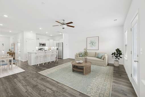 A living room with a couch, coffee table, and a dining table.